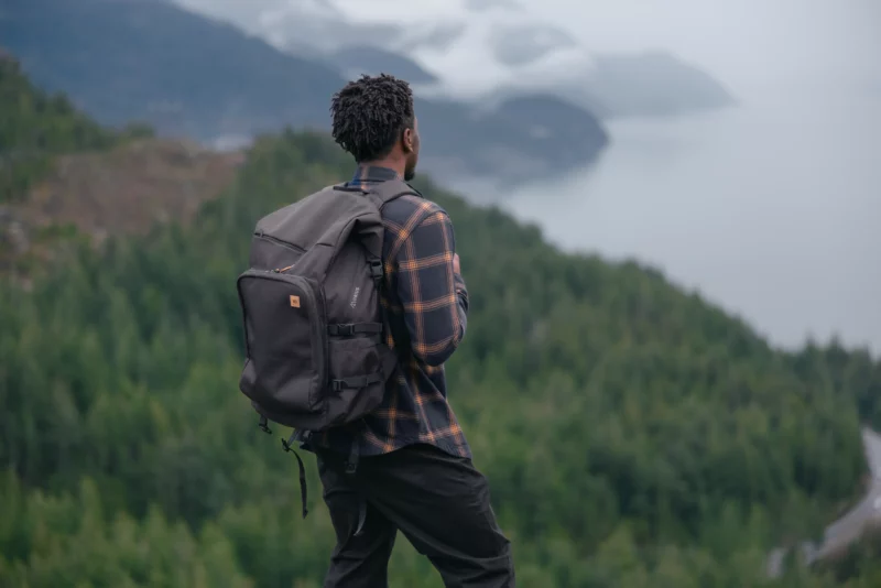 Model wearing tentree sustainable gifts for all Mobius 35L backpack in front of vista.=